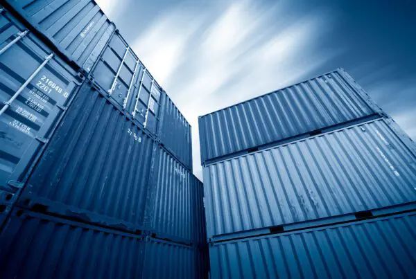 Stacked blue shipping containers against a sunny blue sky, representing Storage on Site's versatile storage solutions.