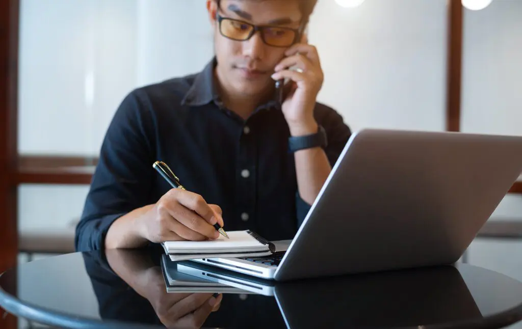 Man on phone call taking notes and gathering container quotes
