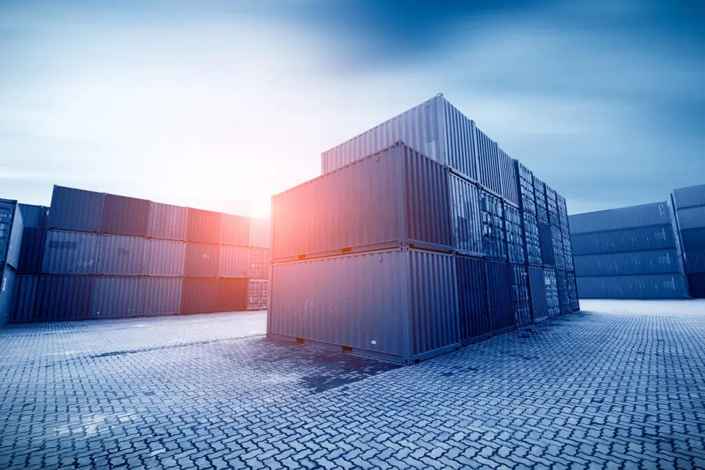 A storage yard with stacked shipping containers under a bright sky, representing sustainable container hire and UK container storage solutions.