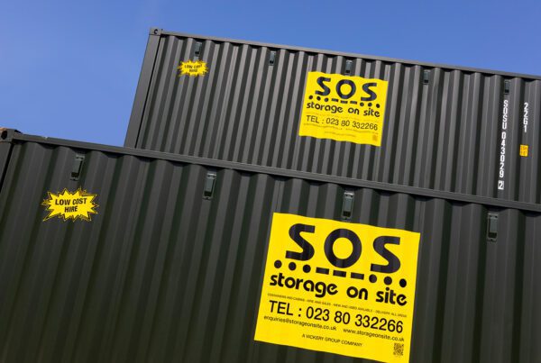 Side view of two stacked green shipping containers with prominent yellow Storage on Site advertising stickers.