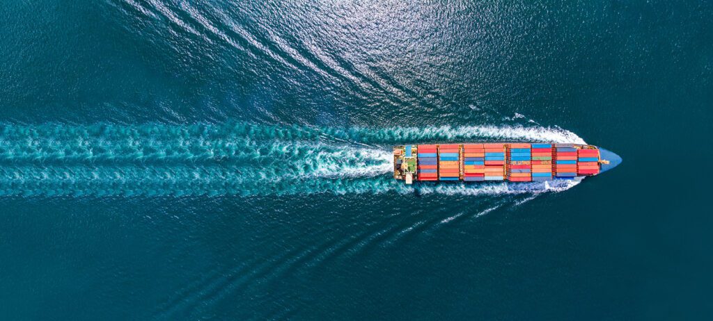 Aerial view of a loaded container ship moving across the deep blue ocean.