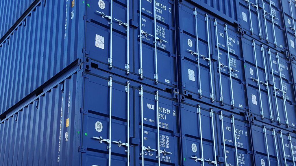 Stack of blue ISO shipping containers with identification codes clearly displayed on their ends.