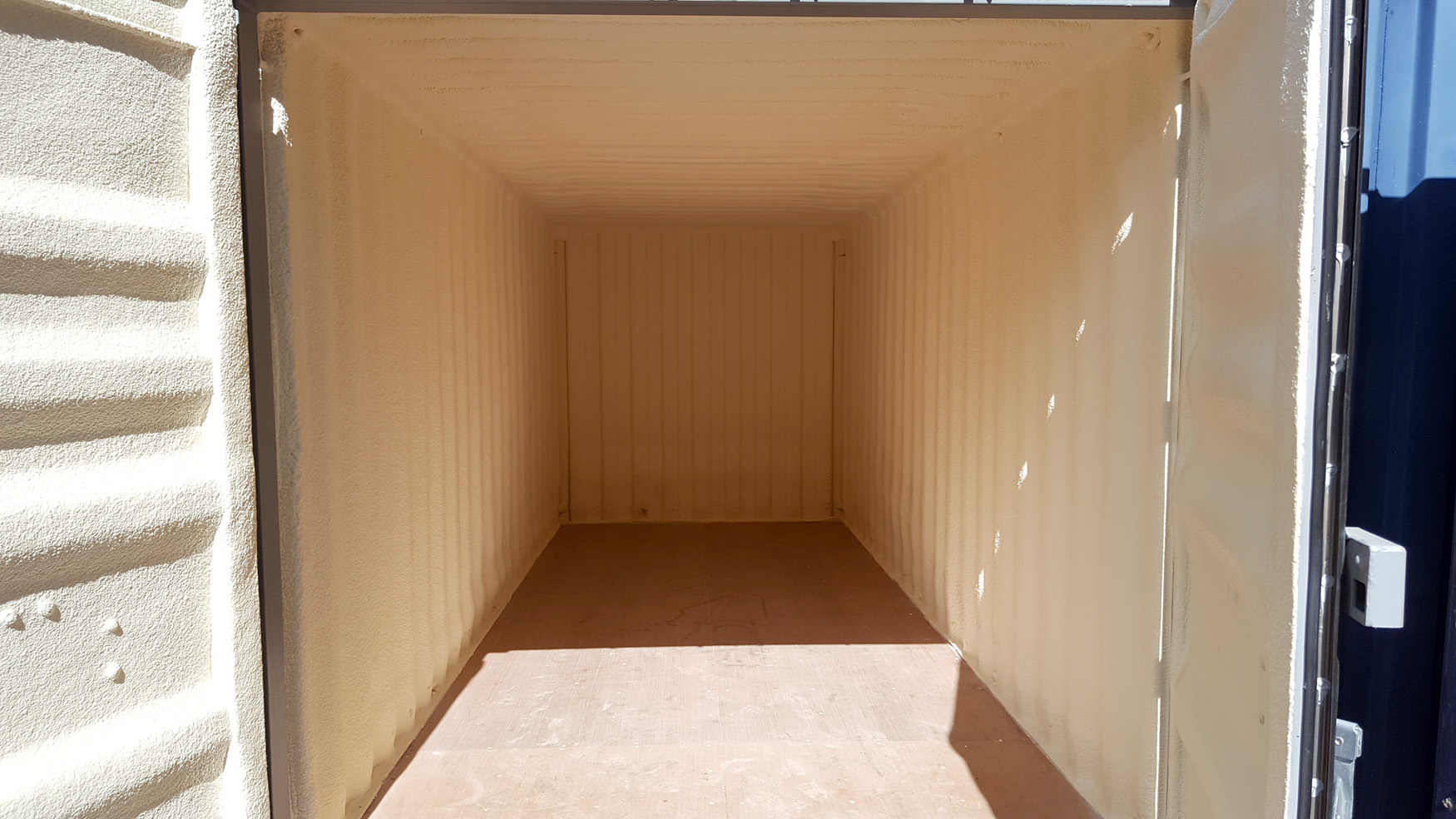 Interior of a furniture grade container with spray foam insulation on walls and roof.