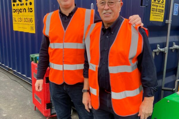 Neil and Pete Vickery from Storage on Site stood in front of an SOS shipping container on site at DIY SOS Southampton